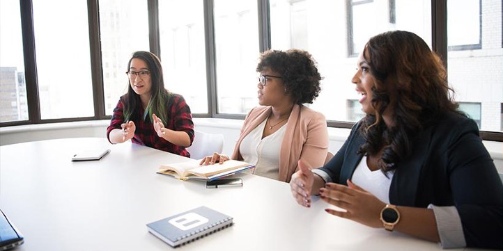 Three women sitting at a conference table