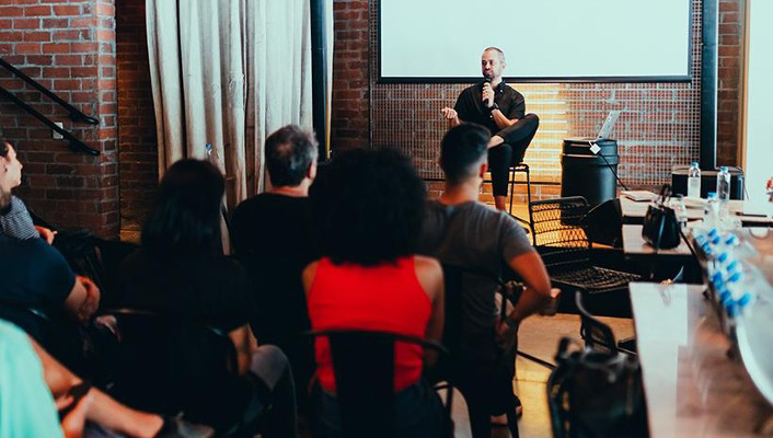 Man on stage speaking to a group of people