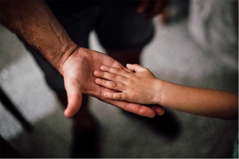 A child hands on top of an adults hand