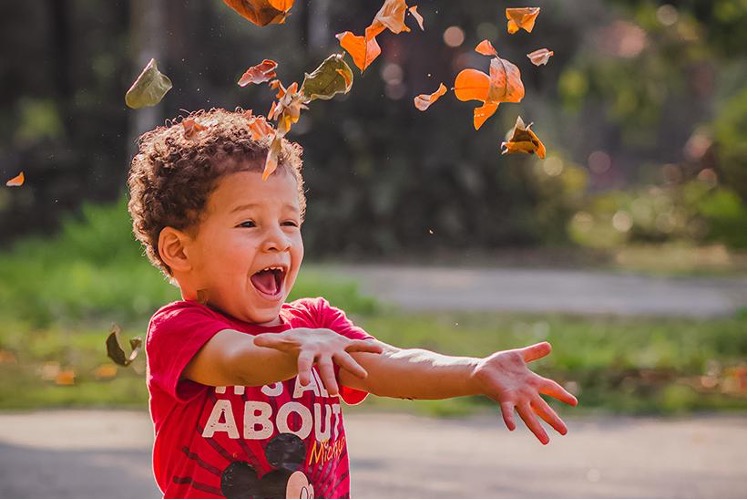 A little kid throwing leaves in the air