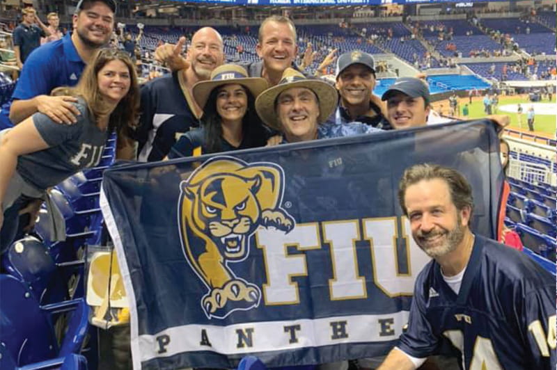 Manuel Becerra, president, Connected Living, Assurance Solutions, his wife Ana Becerra (wearing hat) and Eduardo Hondal, executive diabetes specialty representative, Eli Lilly and Company, with friends and family at the fall 2019 football game that saw the FIU Panthers defeat the University of Miami Hurricanes.