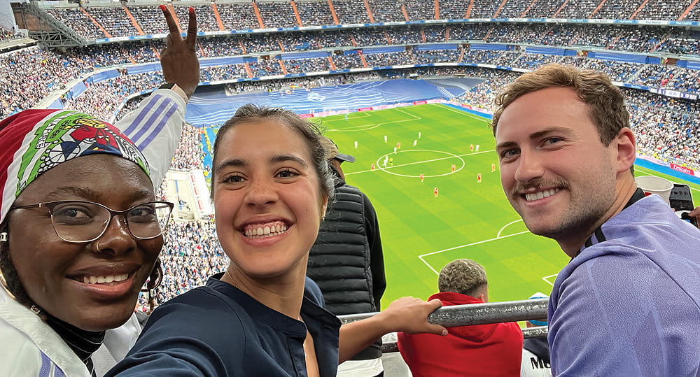 (L to R) FIU Business students Evelie Geffrard, Sofia Moron Marquez and Michael Wright cheered as Real Madrid and Rayo Vallecano faced off at Estadio Santiago Bernabeu on May 24, 2023 in Madrid. Real Madrid won! The game was held during White Week, an annual weeklong event for FIU online MBA students taking the specialization in sports management.
