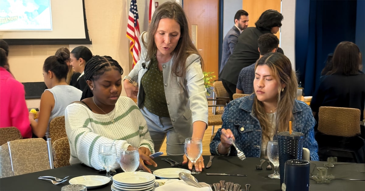 Sammi Rosin Lewis guiding students on selecting the proper eating utensils.