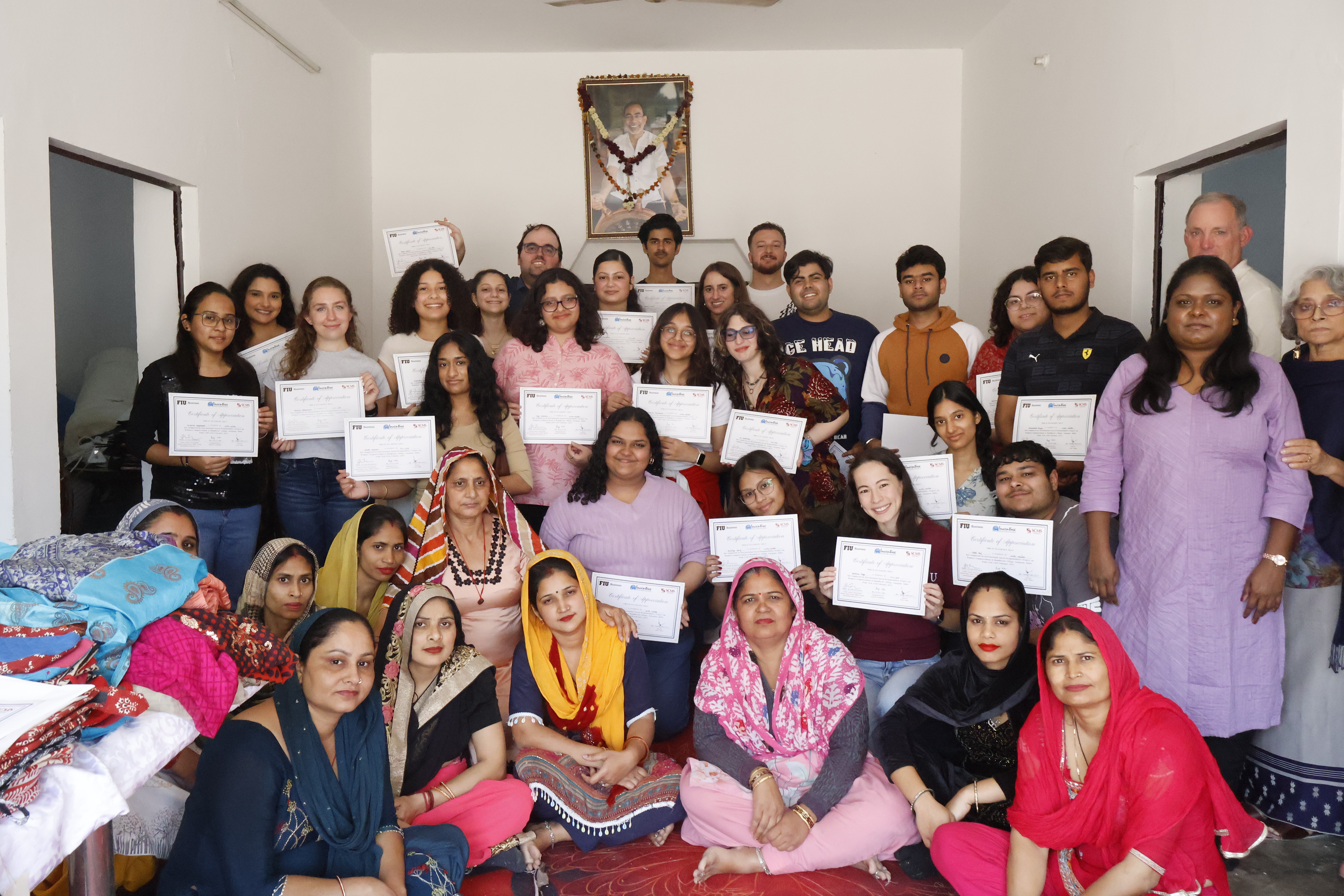 FIU Business students and faculty with the women artisans of Bandhwari Village, holding certificates of appreciation