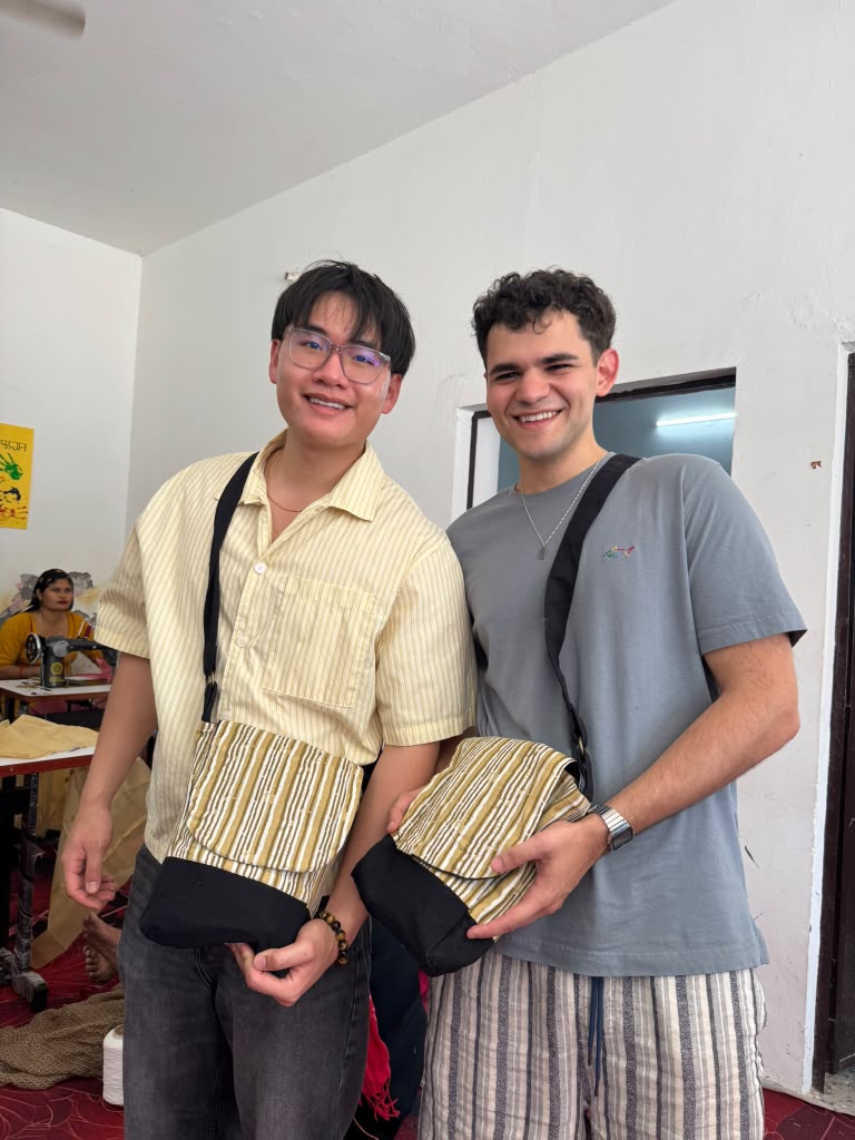 Two FIU students holding handmade bags in the Bandhwari sewing workshop